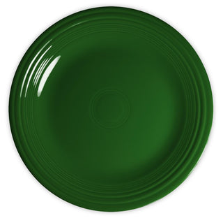 A top-down view of a plain, round, dark green ceramic plate with a glossy finish and concentric circular grooves near the rim. The plate is empty and set against a white background.