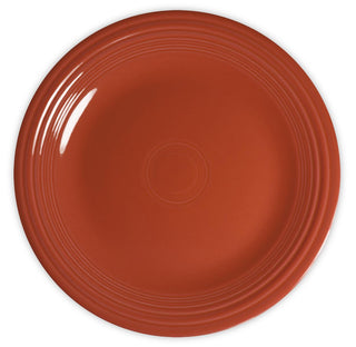 A round, orange ceramic plate with a glossy finish and concentric circular ridges near the rim, viewed from above on a white background.