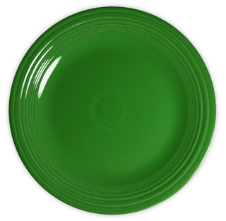 A plain, round green plate with concentric circular ridges along the edge, viewed from above against a white background.