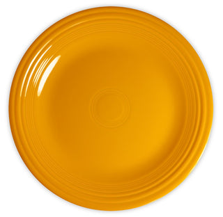 A round, bright yellow ceramic plate with a glossy finish and concentric ridges near the rim, viewed from above on a white background.