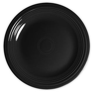 A round, glossy black ceramic plate with concentric circular ridges along the rim, shown from above on a white background.