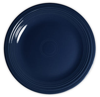 A round, dark blue ceramic plate with a glossy finish and concentric raised rings along the edge, shown from above on a white background.