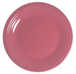 A round, pink ceramic plate with a glossy finish and raised concentric circles near the rim, shown from a top-down view on a white background.