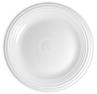 A plain white ceramic plate viewed from above, featuring concentric circular ridges near the edge and a smooth central surface.
