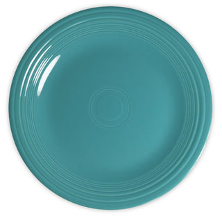 A round, teal-colored ceramic plate with concentric circular ridges near the edge, viewed from above against a white background.