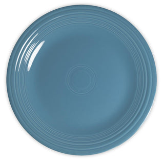A plain, round, blue ceramic plate with a glossy finish and concentric circular ridges near the rim, viewed from above on a white background.