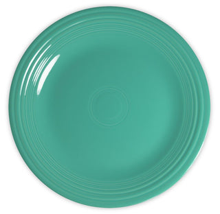 A round, teal ceramic plate with a glossy finish and concentric ring patterns near the rim, photographed from above against a white background.