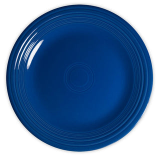 A round, deep blue ceramic plate with concentric circular ridges near the edge, viewed from above against a white background.
