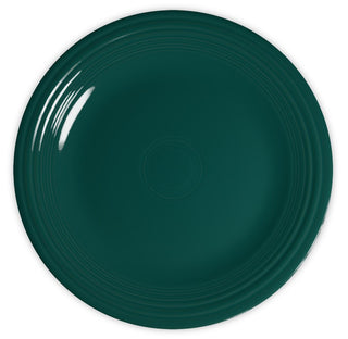 A dark green, round ceramic plate with a glossy finish and subtle concentric ring details near the rim, viewed from above on a white background.