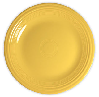 A round, yellow ceramic plate with a glossy finish and concentric circular ridges near the edge, viewed from above against a white background.