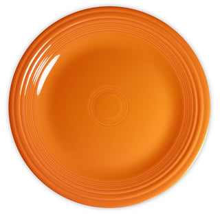 A bright orange ceramic plate with concentric circular ridges near the rim, shown from above on a white background.