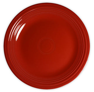 A plain, round, red ceramic plate with a glossy finish and subtle concentric ring patterns along the rim, viewed from above on a white background.
