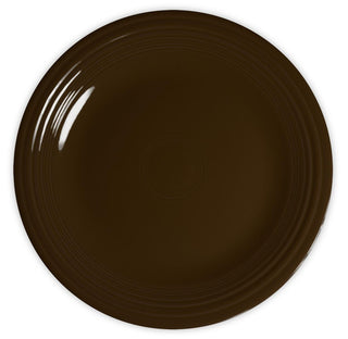 A round, dark brown ceramic plate with a glossy finish and subtle concentric circle patterns along the rim, viewed from above against a white background.
