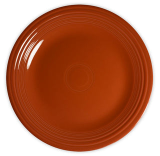 A round, empty, orange ceramic plate with a glossy finish and concentric circular patterns near the edges, viewed from above on a white background.