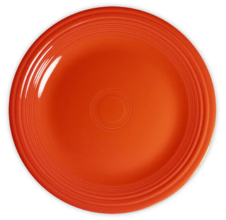 A bright orange ceramic plate with a glossy finish, featuring concentric circle patterns along the rim, viewed from above on a white background.