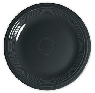A round, dark-colored ceramic plate with a glossy finish and concentric circular ridges along the edge, viewed from above against a white background.