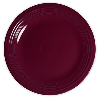A round, deep burgundy plate with a glossy finish and subtle concentric circle patterns along the rim, viewed from above on a white background.