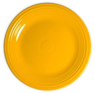 A round, bright yellow ceramic plate with concentric circular ridges near the edge, shown from above on a white background.