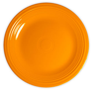 A round, bright orange ceramic plate with a smooth surface and concentric circular ridges near the rim, viewed from above on a white background.