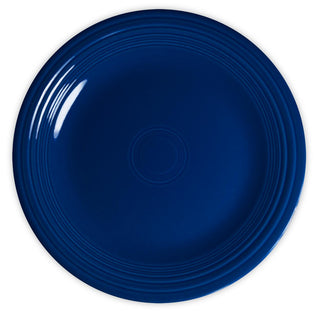 A round, dark blue ceramic plate with concentric ridges near the edge, viewed from above on a white background.