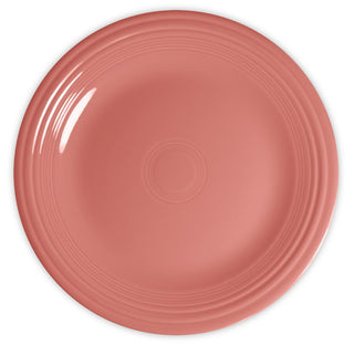 A round, empty plate with a smooth, glossy, coral pink surface and subtle concentric circular ridges near the rim, viewed from above.
