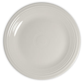 A plain, round, off-white ceramic plate with a smooth surface and concentric raised rings near the rim, shown from above on a white background.