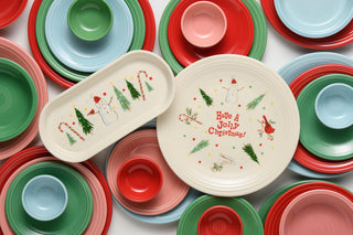 Vibrant red, green, blue, and pink Fiesta plates frame two festive white Fiesta Jolly Christmas Classic Rim Chop Plates (11 3/4 Inch), each adorned with cheerful snowmen, trees, and “Have a Jolly Christmas!”—the ideal backdrop for displaying your favorite holiday fare.