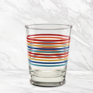 The Moderne Glass Fiesta Vibrant Thin Stripe 15 oz. Tapered Double Old Fashion glass, set of 4, features horizontal red, orange, yellow, and blue stripes and is shown on a white marble surface with a matching marble background. Made in the USA.