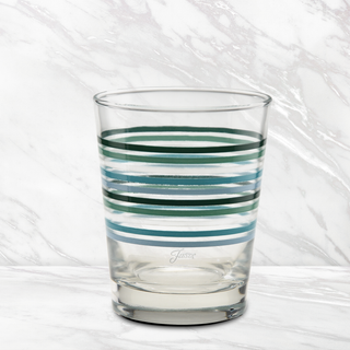 A set of four Moderne Glass Fiesta Aegean Thin Stripe 15 oz. tapered double old fashion glasses features green, blue, and light blue stripes, displayed on a white marble surface with a matching background. Made in the USA.