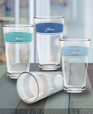 Four Moderne Glass Coastal Blues 16 oz. Frame Coolers, three upright with water, one empty on its side. Each glass in this USA-made set of four features a colored band and logo, displayed on a wooden surface.