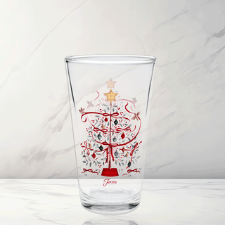 The Moderne Glass Holly Berry Christmas Tree 16 oz. Cooler Glass Set of 4 features clear glass with festive Christmas tree designs, red ribbons, ornaments, a gold star topper, and “Sassa” in red—perfect for holiday entertaining.