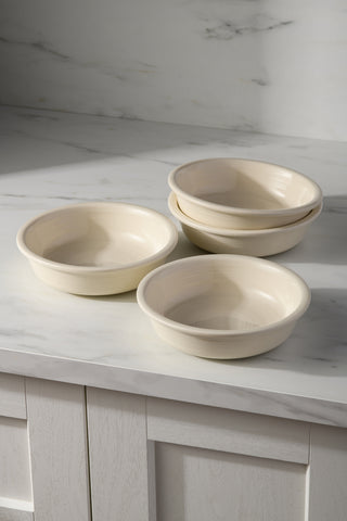 Four Fiesta Linen Classic Rim 6 7/8" Cereal Bowls (19 oz) are arranged on a white marble countertop, with two bowls stacked and two in front, against a backdrop of white marble and light wood cabinetry.