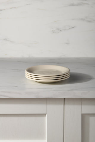 Four Fiesta Linen Set of 4 Classic Rim 7 1/4 Inch Salad Plates are stacked on a white marble countertop with a matching backsplash and paneled cabinets, highlighting durable dinnerware ideal for everyday use.