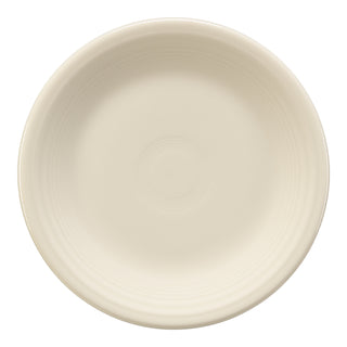 The Fiesta Classic Rim 7 1/4 Inch Salad Plate in Linen is a cream-colored ceramic plate with a slightly raised rim and delicate circular patterns, showcasing American craftsmanship in lead-safe china.