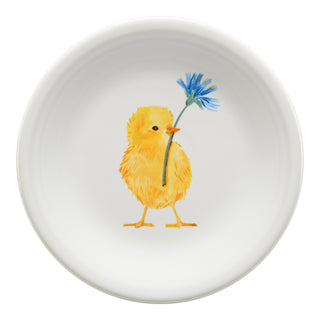 The Fiesta Retired Breezy Floral Easter Classic Rim 7 1/4 Inch Salad Plate is a white vitrified china plate featuring a centered illustration of a fluffy yellow chick holding a blue flower in its beak.