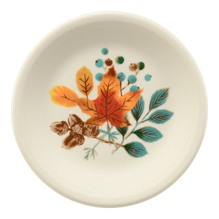 The Fiesta Autumn Fields Classic Rim 7 1/4 Inch Salad Plate is a small white USA-made plate with an orange and yellow autumn leaf, brown acorns, green and blue leaves, and blue dots in its decorative design.