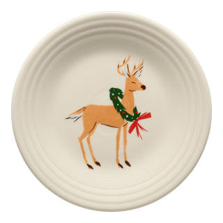 The Fiesta Jolly Christmas Reindeer Classic Rim 9 Inch Luncheon Plate features a cream-colored vitrified china design with a painted reindeer, green wreath, and red bow. Durable, dishwasher safe, and accented with a festive ridged edge.