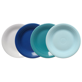 The Fiesta Mixed Coastal Blues Classic Rim 10½ Inch Dinner Plate Set includes four ceramic plates in white, dark blue, teal, and light blue, each with a subtle ridged rim pattern and arranged in a slightly overlapping row.