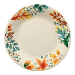 The Fiesta Autumn Fields Classic Rim 10 1/2 Inch Dinner Plate is a round ceramic plate made in the USA, featuring colorful autumn leaves and berries in orange, yellow, green, blue, and brown around the rim with a plain center.