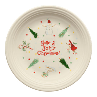 Celebrate the season with the Fiesta Jolly Christmas Classic Rim Chop Plate (11 3/4 Inch), featuring “Have A Jolly Christmas!” in cheerful red lettering, bordered by festive Christmas trees, a snowman, candy cane, cardinal, holly, ice skates, and colorful dots—a perfect holiday serving platter and a charming addition to your Fiesta dinnerware collection.