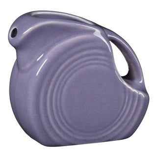 The Fiesta Lavender 5 OZ Mini Disk Pitcher features a vintage round shape, curved handle, glossy finish, and concentric side ridges with a spout—perfect as a collectible accent.