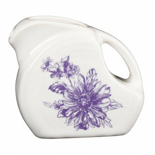 The Fiesta Botanical Floral Lavender 5 OZ Mini Disk Pitcher is a white ceramic piece with a curved handle, spout, and a purple floral design, part of the Botanical Floral Ceramic Dinnerware collection.