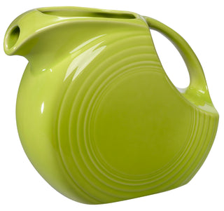 The Retired Fiesta 67 OZ Large Disk Pitcher by Fiesta features a lemongrass glaze, art deco-inspired round design, wide spout, curved handle, and concentric raised rings for decorative appeal. Made in the USA from ceramic.