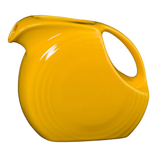 The retired Fiesta 67 OZ Large Disk Pitcher in daffodil features a smooth, glossy finish, subtle concentric ridges, a rounded body, large open handle, and spouted opening—a striking centerpiece from Fiesta.