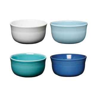 The Fiesta Mixed Coastal Blues All-Purpose 6-Inch 28OZ Gusto Bowls, Set of 4, features white, light blue, teal, and dark blue ceramic bowls. These dishwasher- and microwave-safe bowls are arranged in two rows on a white background.