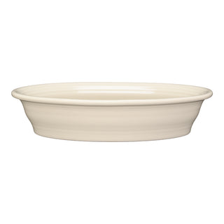 The Fiesta Retired Linen Oval Baker is a 10 1/4-inch, 40 oz ceramic dish in a cream hue. Oven safe and shallow, it features an oval shape and is shown against a white background.