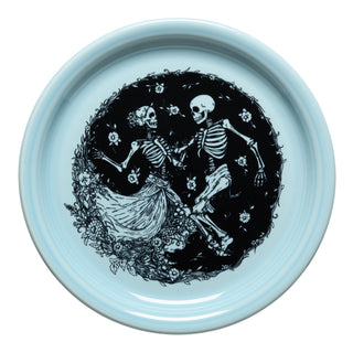 The Fiesta Skeleton Duet Sky Bistro Coupe 9 Inch Luncheon Plate is a lead-safe china plate in light blue, featuring joyful black skeletons dancing among flowers and vines. One skeleton wears a dress. Dishwasher safe.