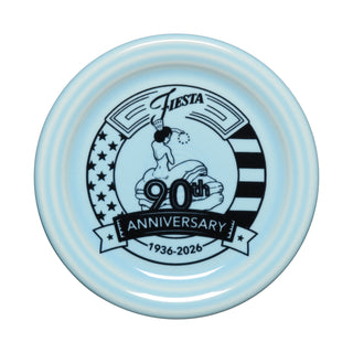 The Fiesta 90th Anniversary 4 3/8 Inch Coaster and Mug Cover by Fiesta features a sky blue base, black and white Fiesta 90th Anniversary 1936-2026 design, dancing woman, stars, and stripes—ideal for collectors.