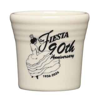 A cream ceramic shot glass, Fiesta 90th Anniversary Linen 1 1/2 OZ Ceramic Shot Glass by Fiesta, features a black illustration of a woman in a dress and Fiesta 90th Anniversary 1936-2026 as a limited edition collectible.