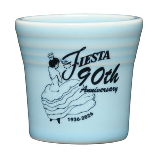 Light blue, color-glazed ceramic shot glass by Fiesta featuring a black illustration of a woman in a flowing dress and Fiesta 90th Anniversary 1936–2026—a limited-edition collectible for Fiesta fans.